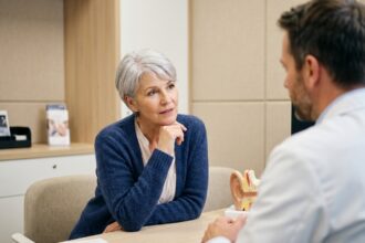 Femme senior en consultation dans un centre d'audition, discutant avec un audioprothésiste dans un environnement moderne et rassurant
