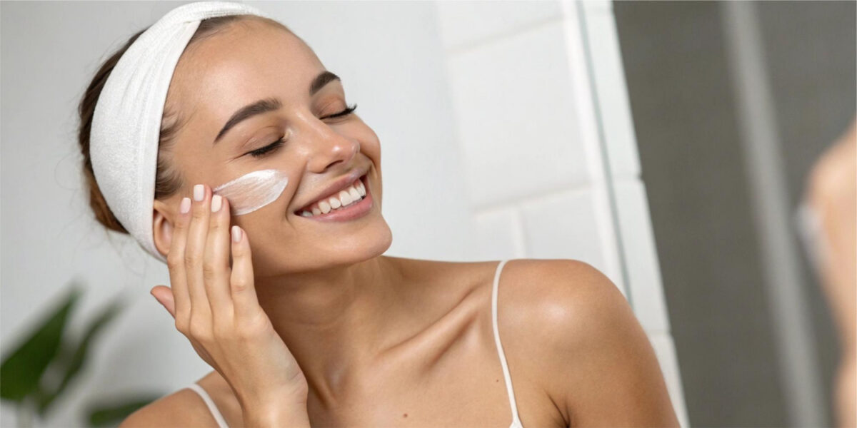 Modèle souriante appliquant une crème pour le visage 